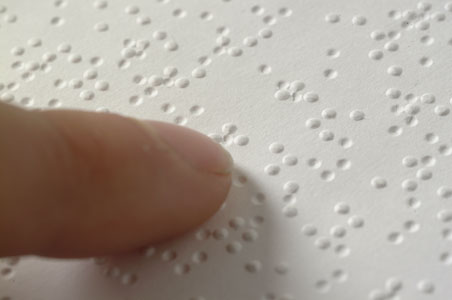 Fingers touching braille dots on a page
