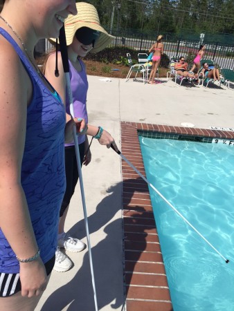 Jakayla finding the edge of the community pool with her cane